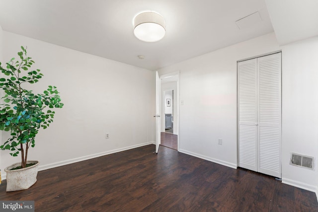 unfurnished bedroom featuring a closet, visible vents, baseboards, and dark wood-style flooring