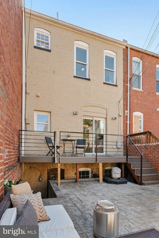 rear view of property featuring stairs, a patio area, and brick siding