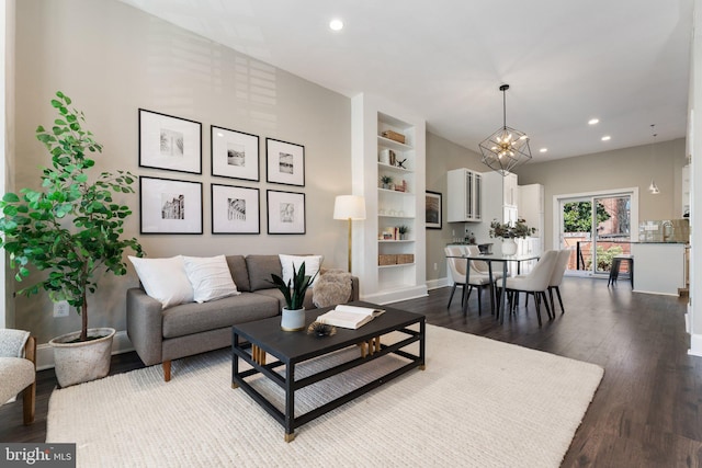 living area featuring built in features, baseboards, recessed lighting, dark wood-type flooring, and a chandelier