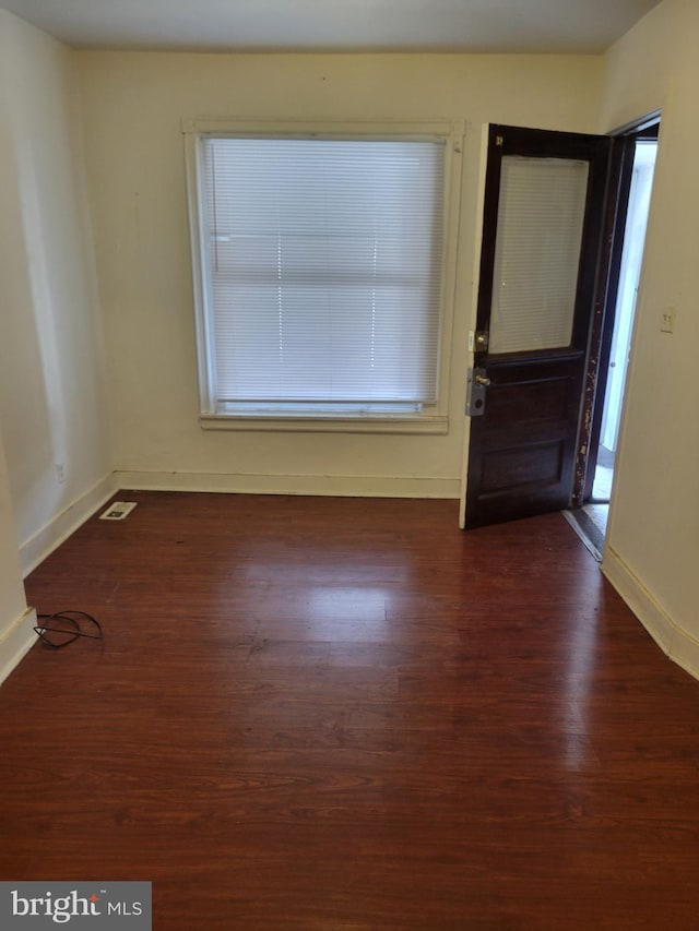 empty room with visible vents, baseboards, and dark wood-style flooring