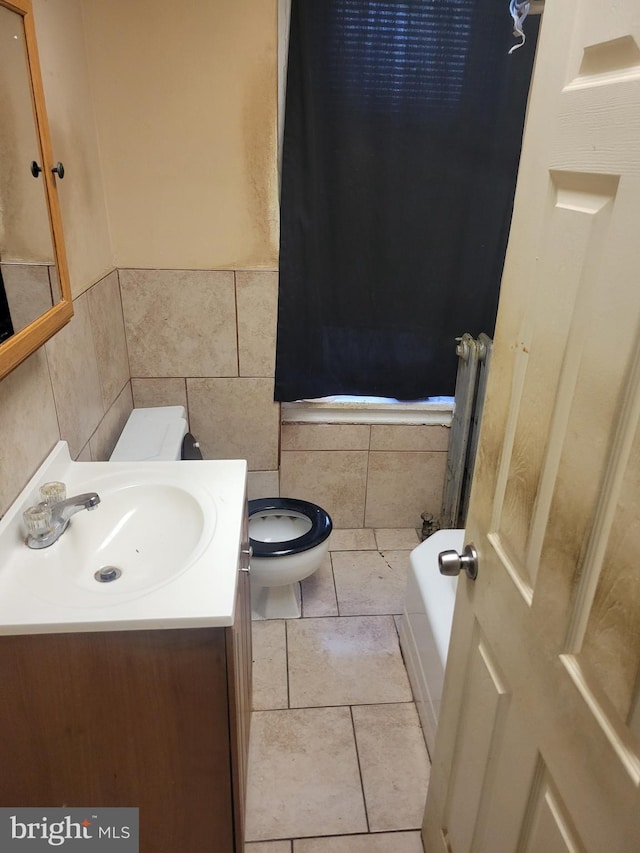 full bathroom featuring tile patterned flooring, tile walls, toilet, a bathtub, and vanity