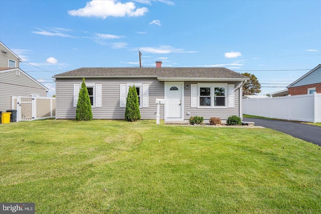 single story home with a front lawn, fence, aphalt driveway, and a chimney