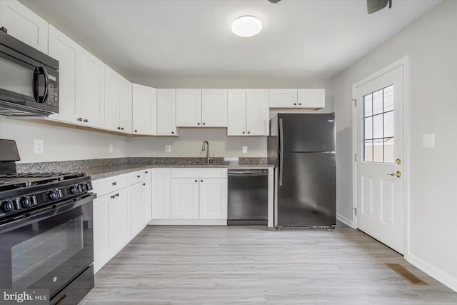 kitchen with a sink, stone countertops, black appliances, and white cabinets