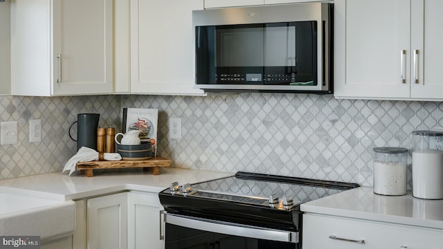 kitchen featuring stainless steel microwave, white cabinets, light countertops, and range with electric cooktop