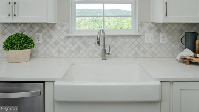 kitchen featuring backsplash, white cabinets, light countertops, and a sink