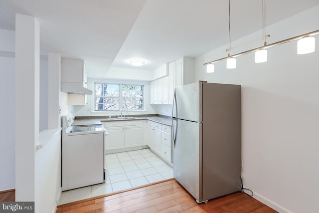 kitchen featuring a sink, washer / clothes dryer, freestanding refrigerator, light wood finished floors, and range