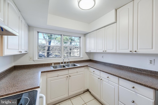 kitchen with a sink, dark countertops, and white cabinetry