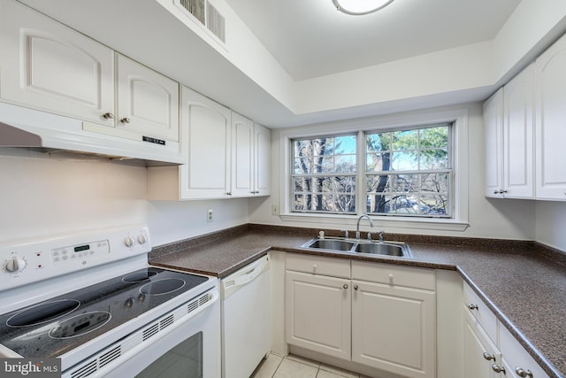 kitchen with visible vents, under cabinet range hood, a sink, dark countertops, and white appliances