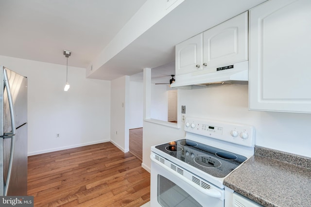 kitchen with light wood finished floors, under cabinet range hood, freestanding refrigerator, white range with electric stovetop, and white cabinets