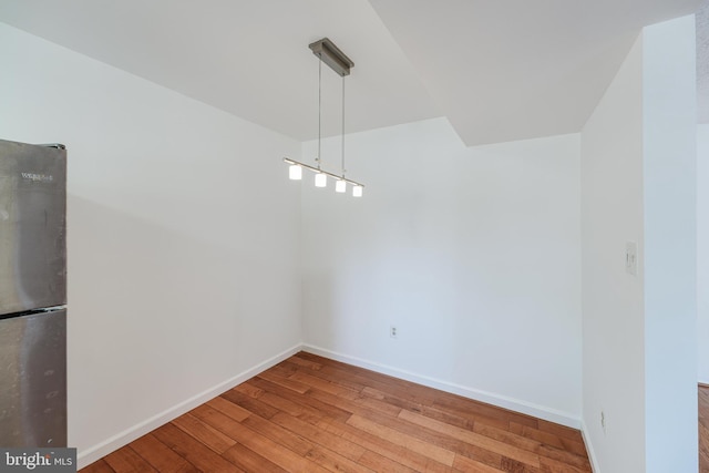 unfurnished dining area featuring baseboards and wood-type flooring