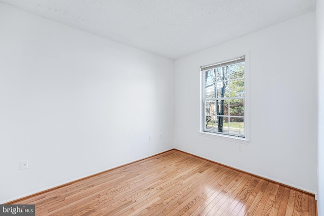 unfurnished room featuring baseboards, a textured ceiling, and light wood finished floors