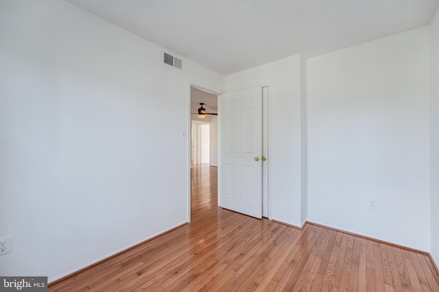 spare room featuring visible vents, a textured ceiling, light wood-type flooring, and baseboards