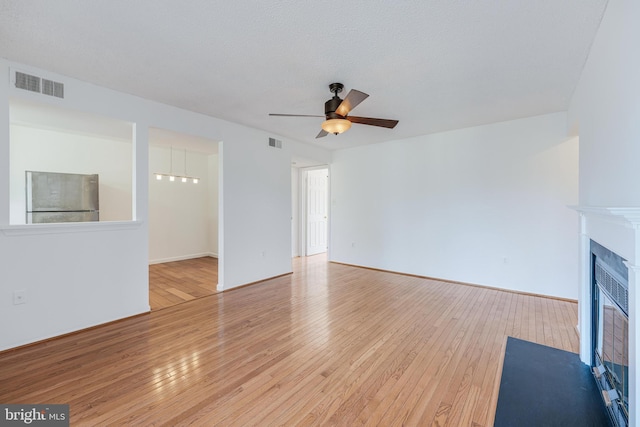 unfurnished living room featuring visible vents, a fireplace with flush hearth, and hardwood / wood-style flooring