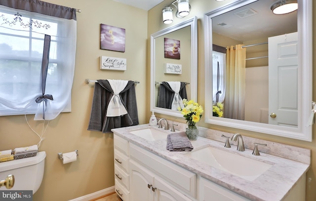 full bath with double vanity, toilet, visible vents, and a sink