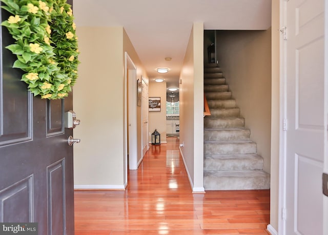 entrance foyer featuring light wood finished floors, stairs, and baseboards