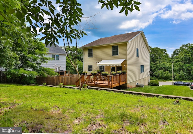 back of property featuring a lawn, fence, and a wooden deck