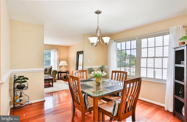 dining area featuring baseboards, a chandelier, and light wood finished floors