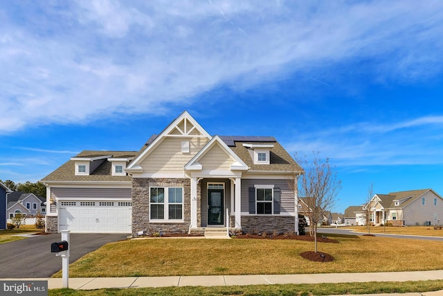 craftsman-style house featuring a front lawn, aphalt driveway, stone siding, a shingled roof, and a garage