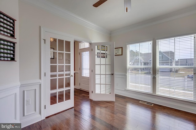 interior space with visible vents, ornamental molding, wood finished floors, french doors, and wainscoting