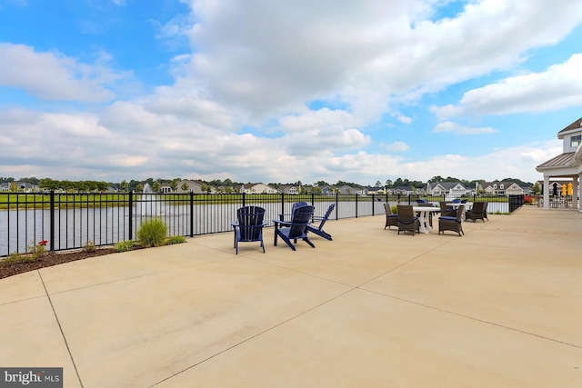 view of patio / terrace with fence, a water view, and a residential view