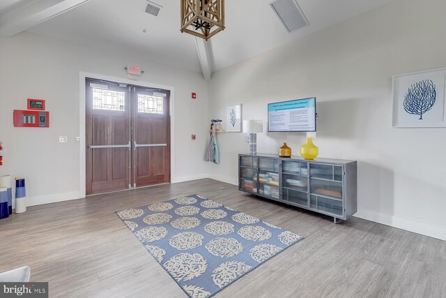 entrance foyer featuring vaulted ceiling with beams, wood finished floors, visible vents, and baseboards