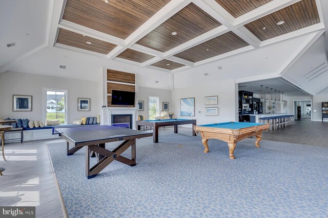 recreation room with coffered ceiling, a fireplace, a towering ceiling, and a healthy amount of sunlight