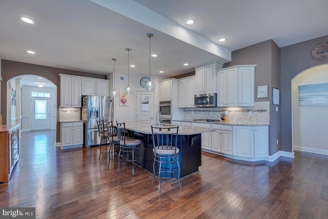 kitchen featuring dark wood-style floors, arched walkways, a sink, appliances with stainless steel finishes, and white cabinetry