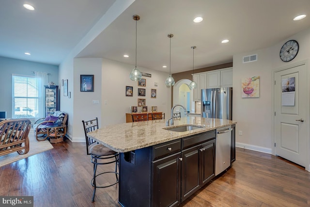 kitchen with dark wood-style floors, visible vents, arched walkways, a sink, and appliances with stainless steel finishes