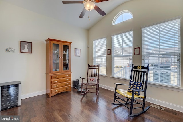 sitting room with heating unit, dark wood-style floors, visible vents, baseboards, and vaulted ceiling