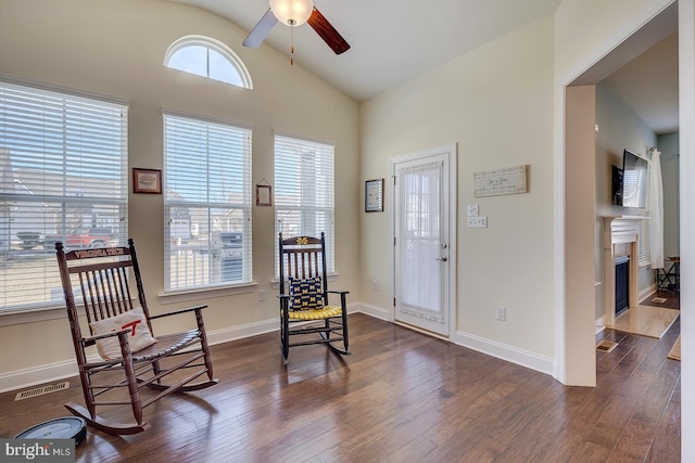 sitting room featuring a ceiling fan, baseboards, visible vents, dark wood-type flooring, and vaulted ceiling