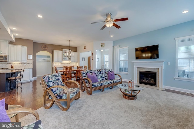 living room with a glass covered fireplace, recessed lighting, light wood-style floors, and baseboards