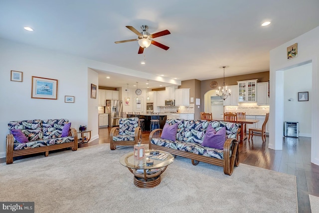 living room featuring ceiling fan with notable chandelier, recessed lighting, wood finished floors, and baseboards