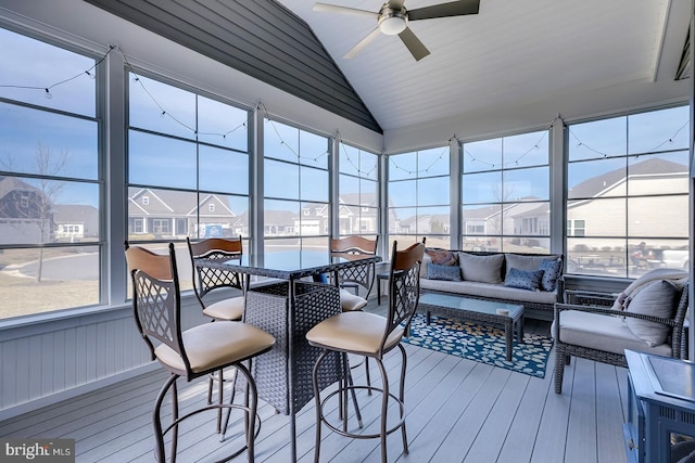 sunroom featuring a wealth of natural light, a residential view, ceiling fan, and lofted ceiling