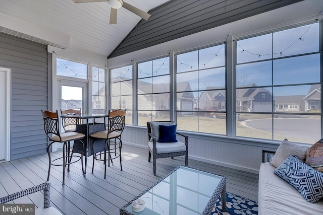 sunroom / solarium with a residential view, ceiling fan, and lofted ceiling