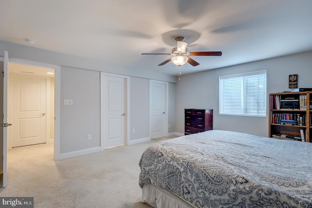 carpeted bedroom featuring baseboards, two closets, and ceiling fan