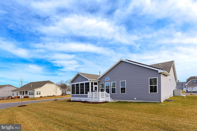 rear view of house with a residential view, a lawn, and a sunroom