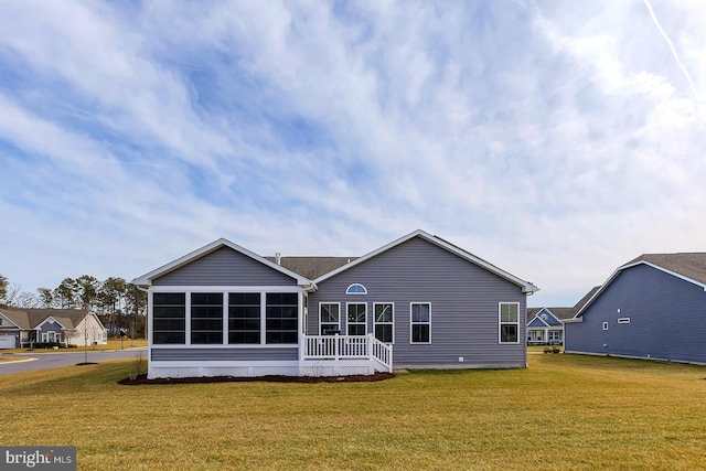 rear view of house featuring a yard and a sunroom