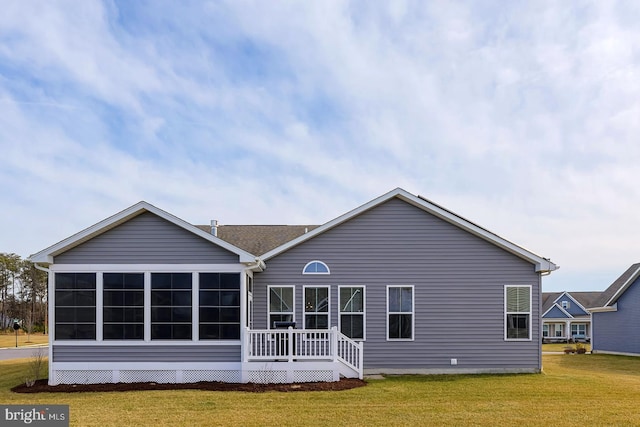 rear view of house featuring a yard, a wooden deck, and a sunroom