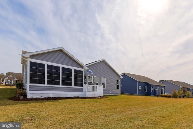 back of house featuring a yard and a sunroom