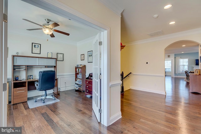 office with arched walkways, wood finished floors, and crown molding