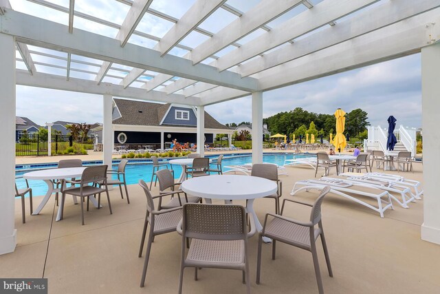 view of patio with a pergola, a community pool, and fence