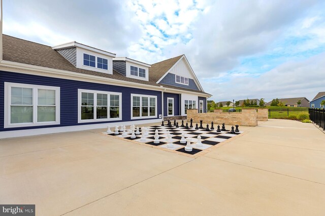 view of front of home with a patio area, roof with shingles, and fence