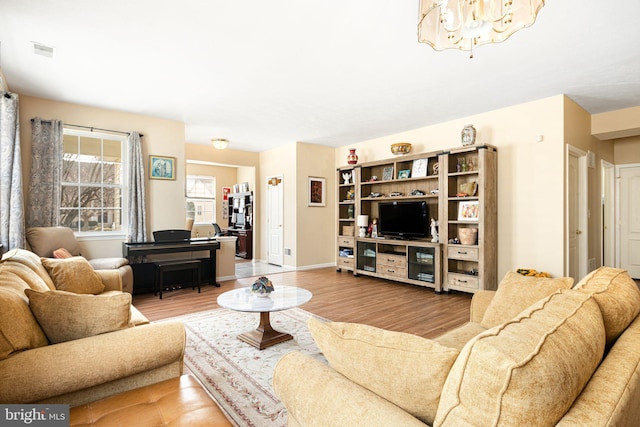 living room with visible vents, baseboards, an inviting chandelier, and wood finished floors