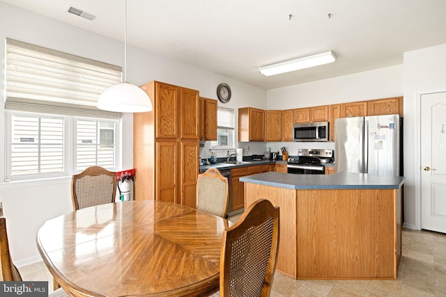 kitchen with brown cabinetry, visible vents, hanging light fixtures, appliances with stainless steel finishes, and dark countertops