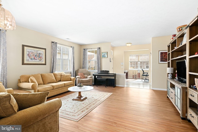 living area with a healthy amount of sunlight, baseboards, and light wood-style floors