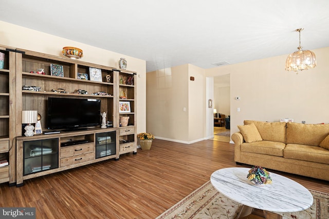 living area featuring baseboards, dark wood-type flooring, and an inviting chandelier