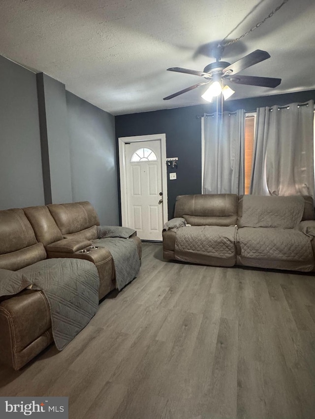 living area featuring a textured ceiling, a ceiling fan, and wood finished floors