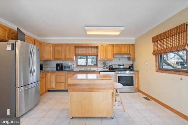 kitchen with under cabinet range hood, light tile patterned floors, appliances with stainless steel finishes, and a sink