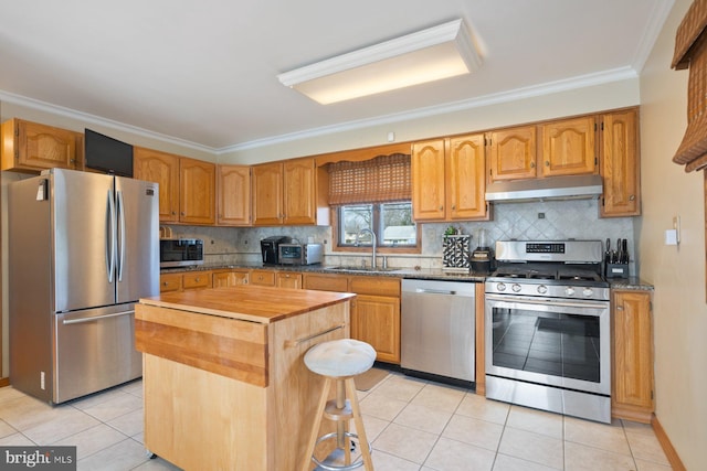 kitchen featuring crown molding, under cabinet range hood, stainless steel appliances, wood counters, and a sink