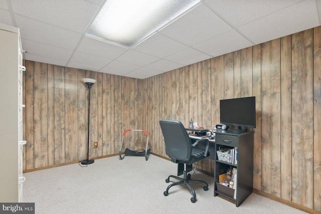 carpeted office with wood walls and a paneled ceiling